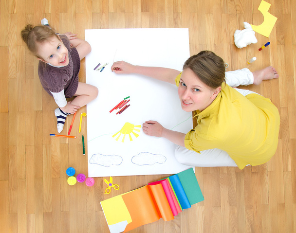 Young woman and little girl drawing together sitting on the floor. Top view. - Foto, Bild