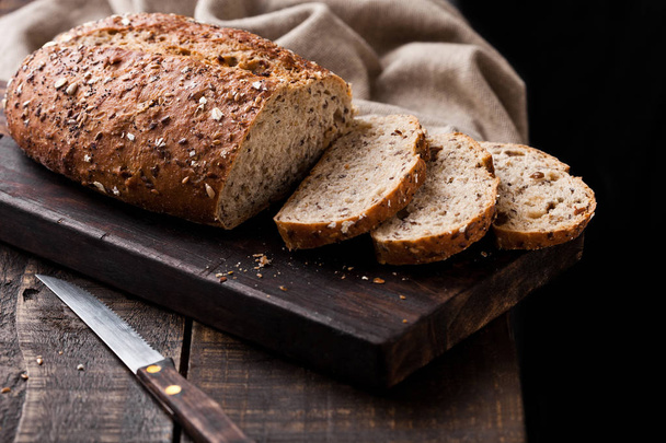 Pão fresco assado com toalha de cozinha e faca
 - Foto, Imagem