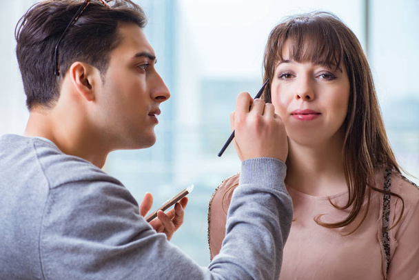 Man doing make-up for cute woman in beauty salon - Фото, зображення