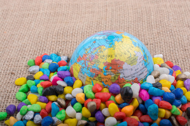 Model globe placed amid colorful pebbles - Fotó, kép