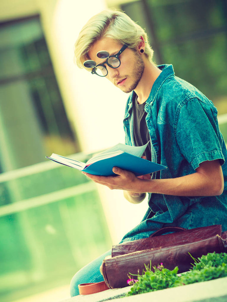 Hipster guy holding notebook sitting on ledge - Photo, image