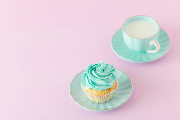 Cupcake with mint cream decoration and cup of milk and coffe on pink pastel background. Mother's day greeting card - Fotó, kép