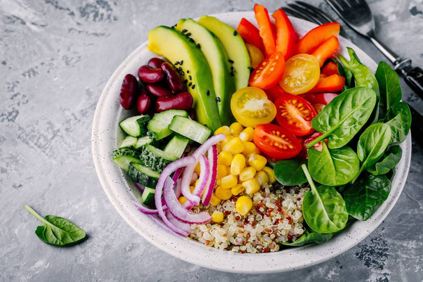Gezond vegan lunch Buddha bowl. Avocado, quinoa, tomaat, komkommer, rode bonen, spinazie, rode ui en rode paprika groenten Salade.  - Foto, afbeelding
