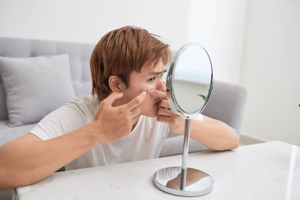 Asiatico uomo guardando specchio e popping un brufolo
 - Foto, immagini