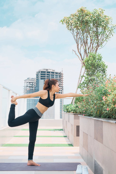 Jeune femme asiatique en tenue de sport pratiquant le yoga en plein air
 - Photo, image