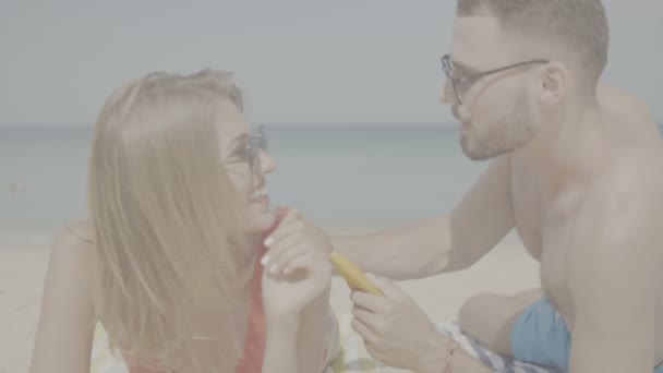 Güzel çift sırasında yaz tatil / mutlu çift sahilde, kadın - ağır çekimde video güneş koruyucu güneş kremi koyarak adam güneş Bronzlaştırıcı Losyon uygulamak - Video, Çekim