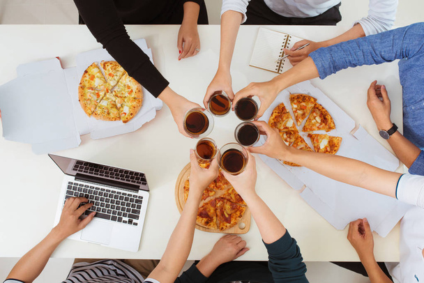 Almuerzo y concepto de personas. Feliz equipo de negocios comiendo pizza en la oficina
 - Foto, imagen