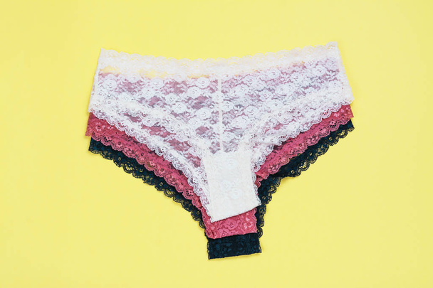 Set of beautiful lace panties on yellow background - 写真・画像