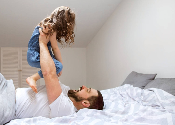 Dad and daughter have fun at home on the bed. Father's Day. - Foto, imagen