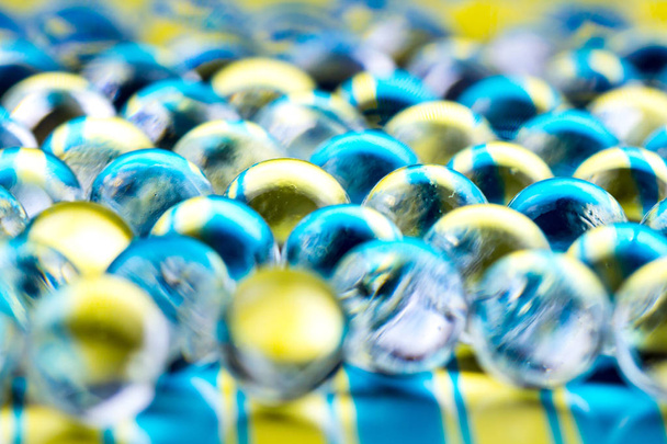 Синие и желтые гелевые шарики для воды. Макрофотография может быть использована как для рекламы или косметики, так и для медицины. Абстрактный фон
. - Фото, изображение
