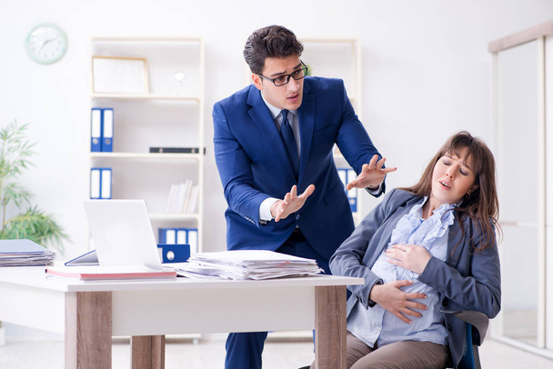 Pregnant woman struggling in the office and getting colleague he - Zdjęcie, obraz