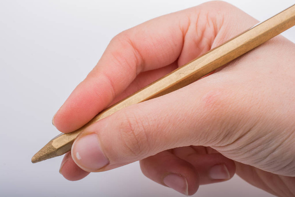Χέρι κρατώντας ένα χρυσό χρώμα μολύβι σε λευκό φόντο - Φωτογραφία, εικόνα