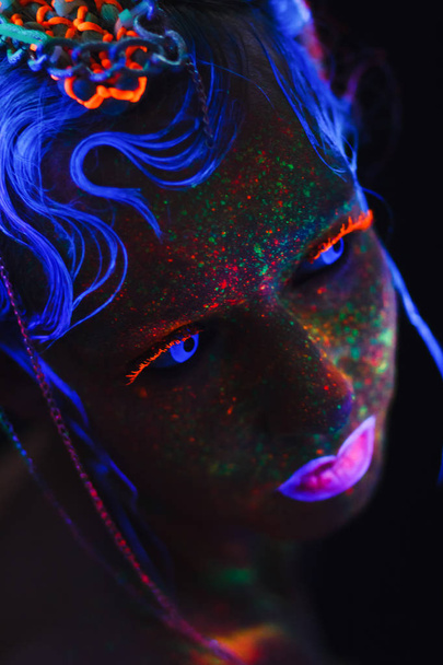 Neon kız portresi. Parlak yüzünde sıçramalarına. Koyu mavi neon lensler ile model. Cadılar Bayramı için görüntü. - Fotoğraf, Görsel