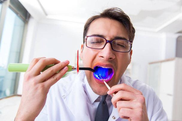 Divertido dentista con luz de curado en concepto médico - Foto, imagen