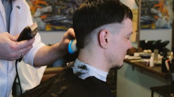 Hairdresser cuts an electric razor with a man in a barbershop - Footage, Video
