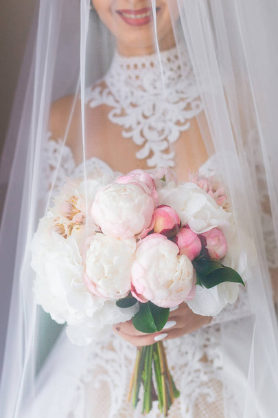 美しいドレスを着てエレガントな花嫁の結婚式のブーケを保持し、ベールで覆われています。 - 写真・画像