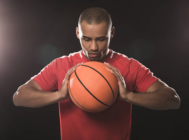 Young athletic man concentrating on orange ball - 写真・画像