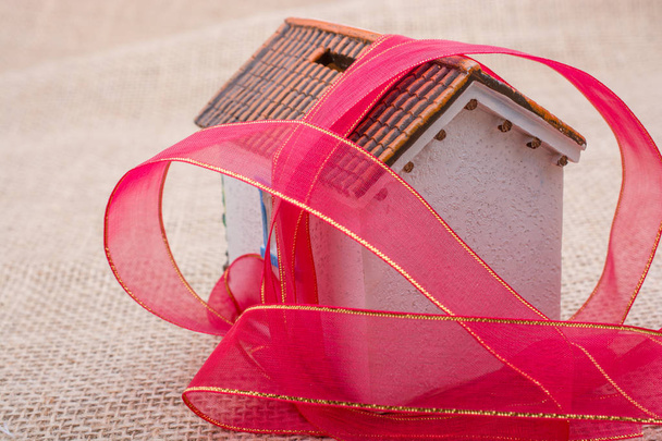 Banda rosa envuelta alrededor de una casa modelo sobre un fondo marrón
 - Foto, Imagen