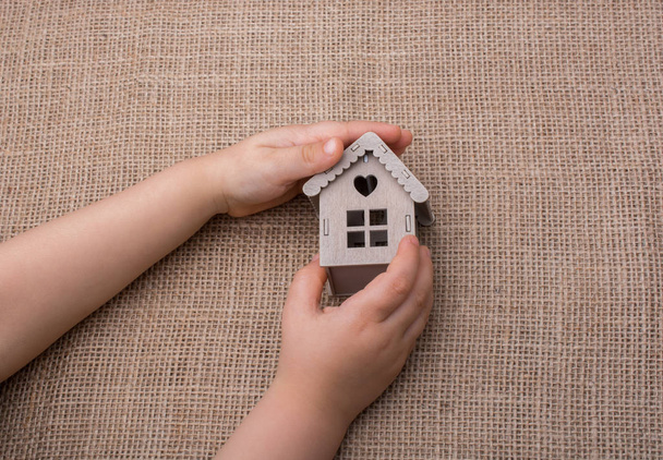 Niño sosteniendo una casa modelo sobre un lienzo de lino - Foto, imagen