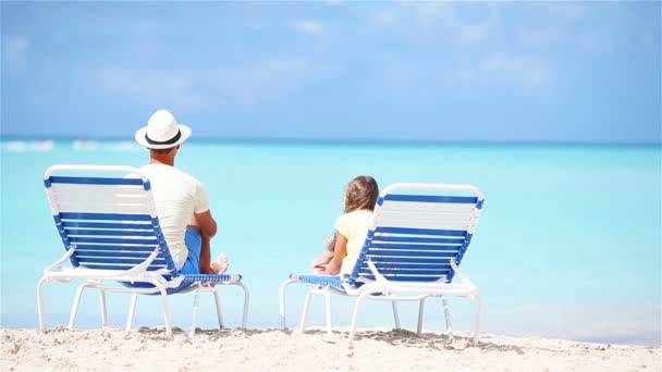 Πατέρας και κόρη σε τροπική παραλία κάθεται στο ανάκλιντρο απολαμβάνοντας τη θέα του Ατλαντικού Ωκεανού - Πλάνα, βίντεο