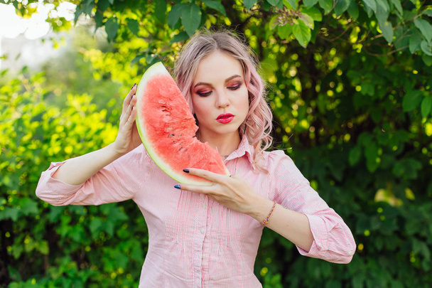 Beautiful young woman with pink hair enjoying watermelon - Foto, immagini