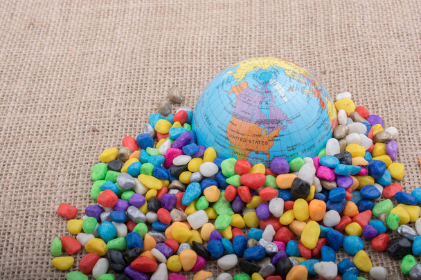 Модельний глобус розміщений серед різнокольорових гальки
 - Фото, зображення