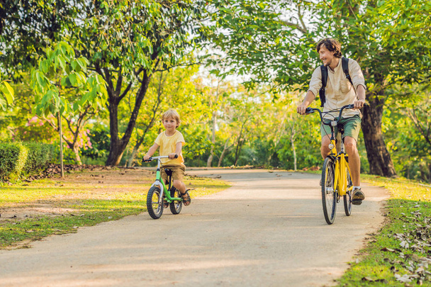 Father and son riding bikes outdoors and smiling - Fotoğraf, Görsel