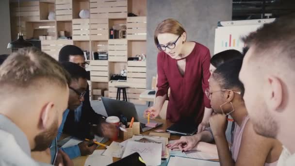 Női csapat vezetője bemutatja új feladatok a munkavállalók. Boldog többnemzetiségű kollégák brainstorming irodában ülés 4k. - Felvétel, videó