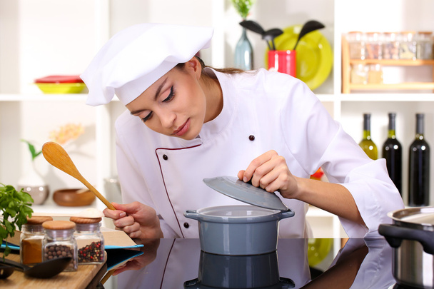 Young woman chef cooking in kitchen - 写真・画像