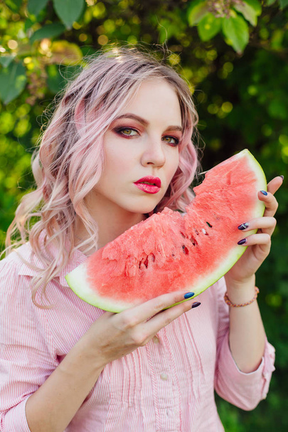 Beautiful young woman with pink hair enjoying watermelon - Foto, Bild