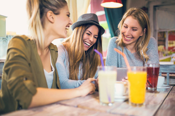 Female friends enjoying conversation and drinking beverages at cafe - Fotografie, Obrázek