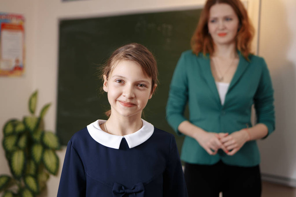 Lány kérdéseire a tanárok közelében egy iskolaszék - Fotó, kép