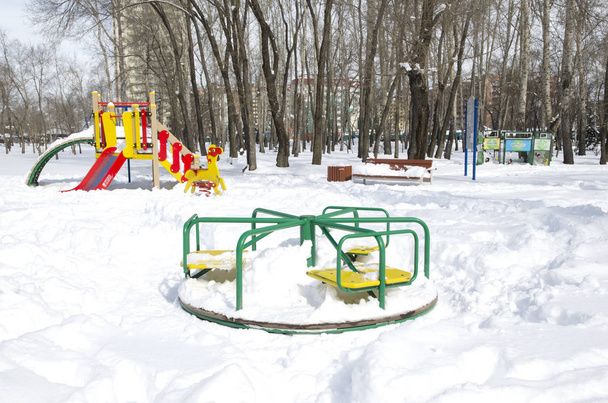 carrousel dans un parc d'attractions public pour enfants enneigé. Russie, Sibérie. Printemps 01 avril
 - Photo, image
