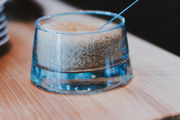 Bruine suiker in lepel en servies op servet - Foto, afbeelding