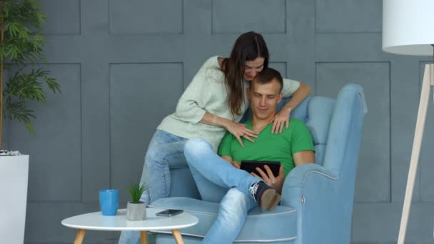 Casual couple sharing tablet pc siting on armchair - Video