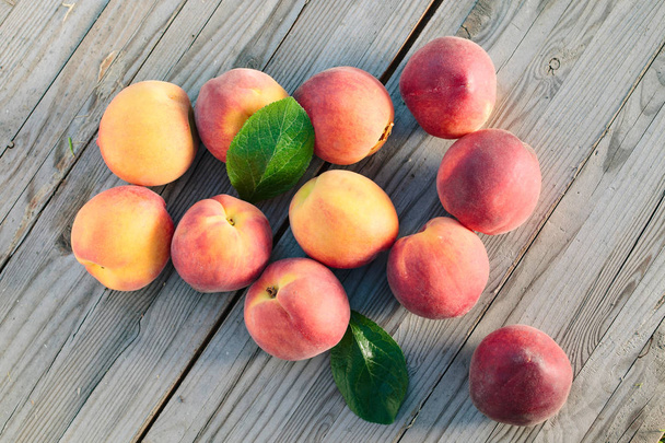Fresh peaches fruits with leaves  on wooden rustic background. - Photo, Image