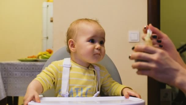 Mutter füttert das Baby mit Babynahrung aus dem Glas, das Baby ist frech und will nichts essen - Filmmaterial, Video