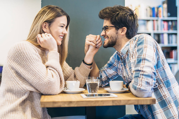 Ζευγάρι πίνει καφέ στο τραπέζι στην καφετέρια και κρατώντας τα χέρια - Φωτογραφία, εικόνα