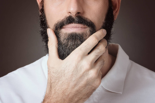 暗い背景上髭に触れる男の Croped イメージ - 写真・画像