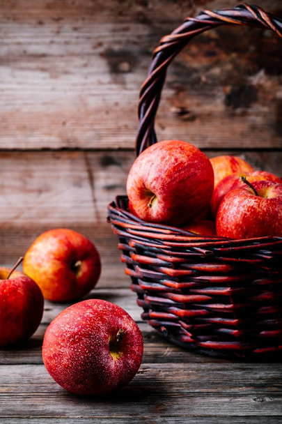 Красные спелые яблоки в корзине на деревянном фоне - Фото, изображение