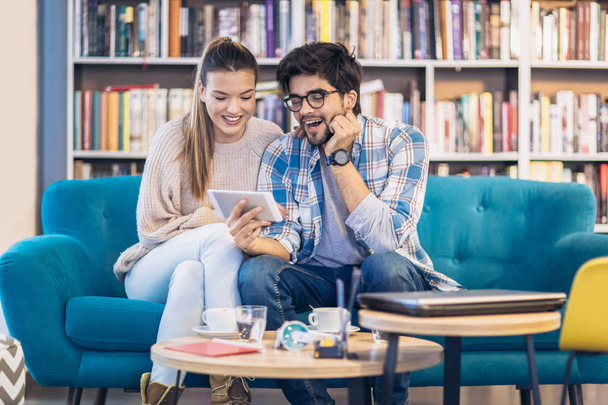 Young couple having fun and using digital tablet indoor in cafe - Photo, image