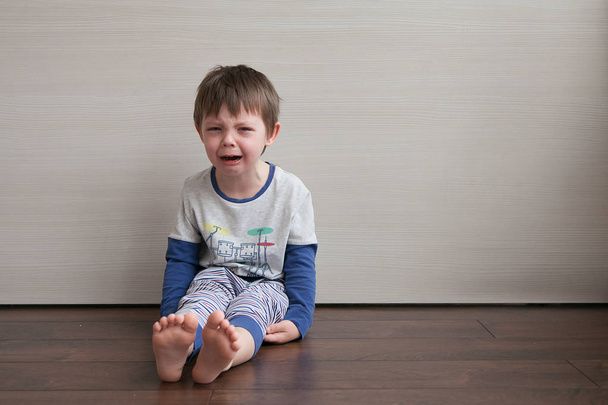 Chlapec je naštvaná, pláč a protestovali. Sedí v pokoji na podlaze. - Fotografie, Obrázek