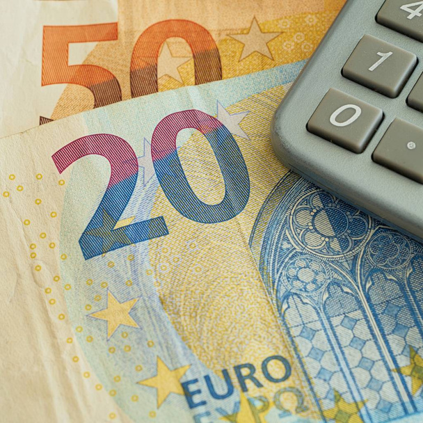 Eurobiljetten en rekenmachine liggen op een tafel - Foto, afbeelding