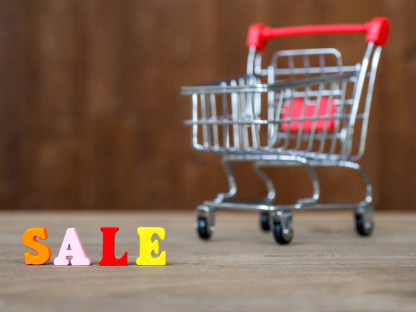 Colorful wooden word SALE on wooden table and shopping cart and background wooden. English alphabet made of wooden letter color. The concept of shopping and Discount festival - Fotografie, Obrázek