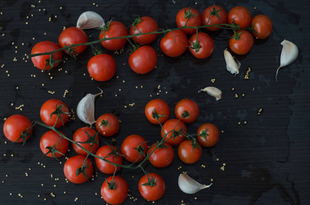 Tomatoes and garlic, on black background with spilled spices - Photo, Image