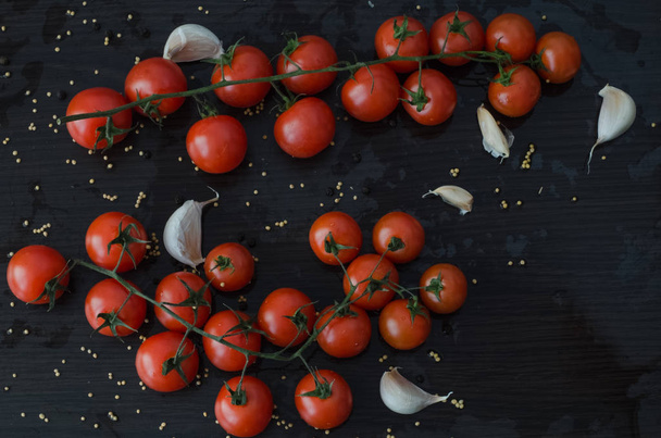 Tomatoes and garlic, on black background with spilled spices - Photo, Image