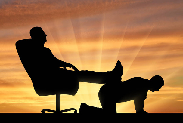 Silhouet van een egoïstische man zittend in een stoel, gooide terug zijn benen op de achterkant van een man - Foto, afbeelding