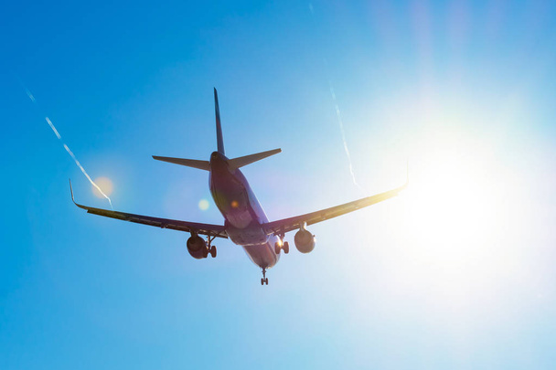 Utasszállító repülőgép repül közel a nap vakító fény a kirakodás, a steam jet vortex szárnyakkal. - Fotó, kép