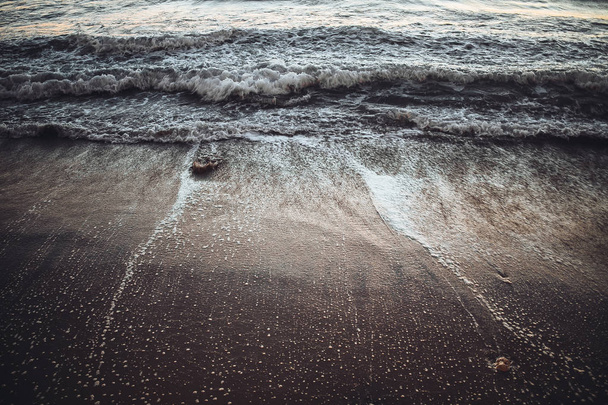 γκρο πλαν φωτογραφία καθαρή θάλασσα κύματα με αφρό στην αμμώδη παραλία στο ηλιοβασίλεμα - Φωτογραφία, εικόνα