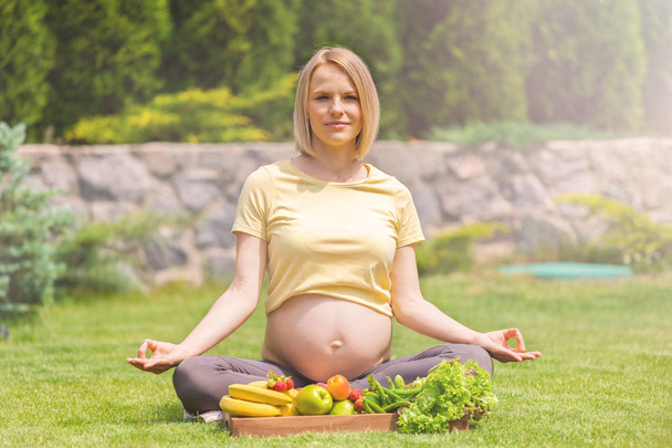 Pregnant woman practicing meditation and relaxation in nature - Φωτογραφία, εικόνα